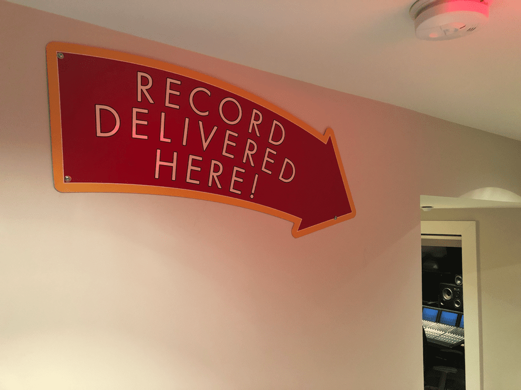 "RECORD DELIVERED HERE!" sign in studio hallway